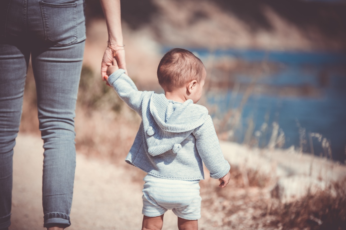 Bébé tient la main, à la plage devant les dunes