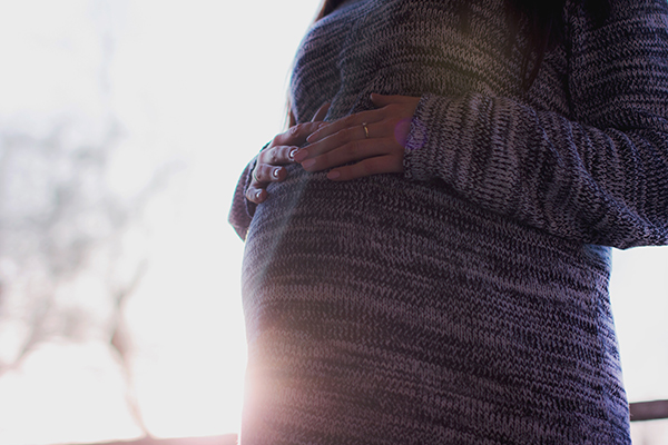 Une femme enceinte, la main sur son ventre